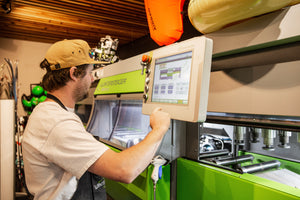 Technician operating a Wintersteiger ski tuning machine at Nomad Sports in Teton Village, Wyoming, preparing equipment for optimal performance on the slopes.