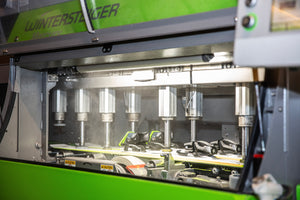 Close-up of a Wintersteiger ski tuning machine in action, applying precision to skis with bindings at Nomad Sports in Teton Village, Wyoming.