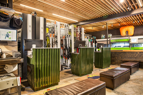 Rental area inside Nomad Sports in Teton Village, Wyoming, featuring ski equipment and modern check-in counters with a warm wooden warm welcoming design.