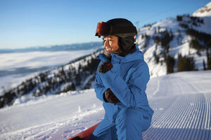 Smiling skier in blue Gore-Tex gear, enjoying the snowy peaks of Jackson Hole, ready for an adventure on the slopes.