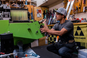 Skilled technician adjusting a ski tuning machine at Nomad Sports in Teton Village, Wyoming, preparing skis for optimal performance on the slopes.